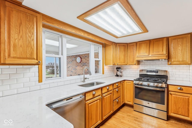 kitchen with stainless steel appliances, light hardwood / wood-style floors, sink, and decorative backsplash