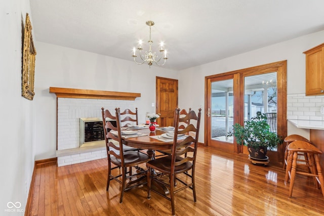 dining space featuring an inviting chandelier, a fireplace, and light hardwood / wood-style flooring