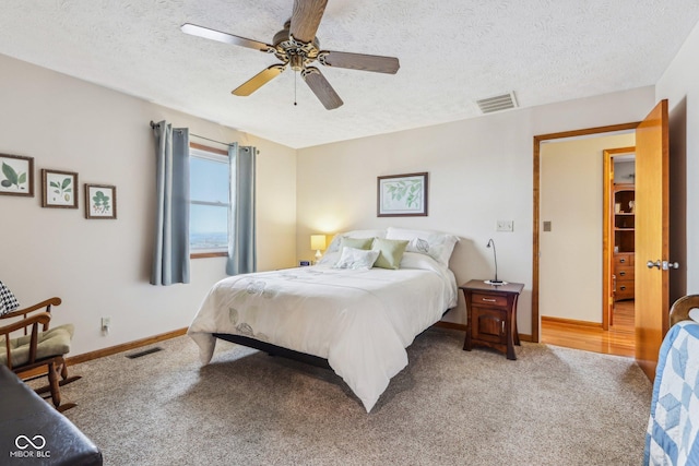 bedroom with ceiling fan, carpet, and a textured ceiling