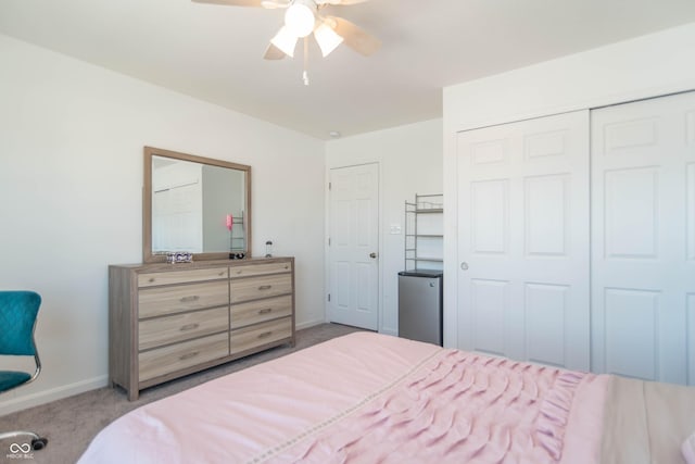 bedroom with light colored carpet, ceiling fan, and a closet