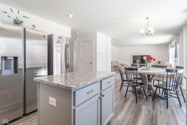 kitchen with stainless steel refrigerator, hanging light fixtures, a center island, light hardwood / wood-style floors, and stainless steel fridge with ice dispenser