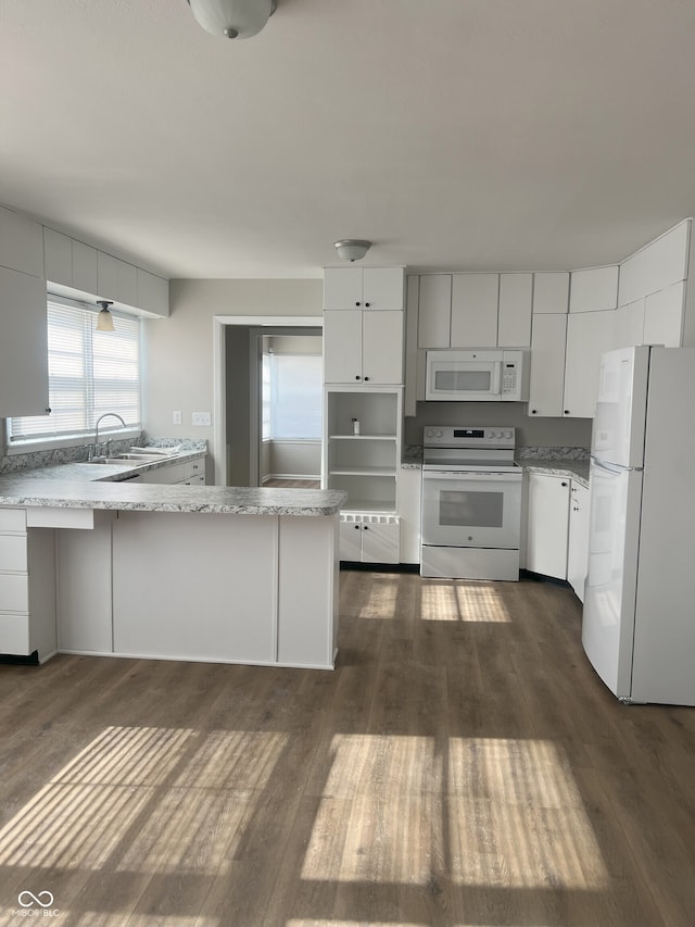 kitchen featuring dark wood-type flooring, white cabinets, white appliances, and kitchen peninsula