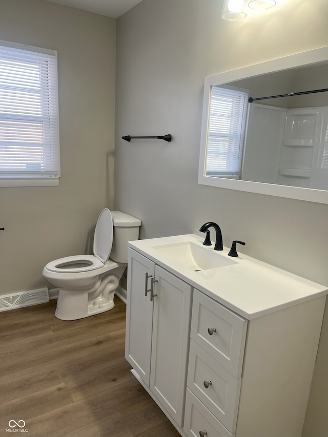 bathroom featuring vanity, hardwood / wood-style floors, toilet, and a healthy amount of sunlight