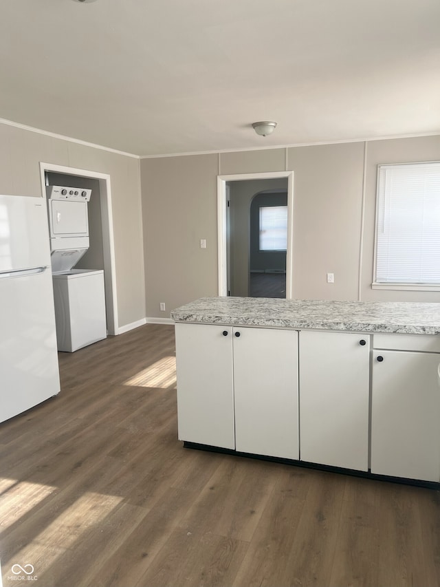 kitchen featuring dark hardwood / wood-style floors, stacked washer and clothes dryer, white refrigerator, light stone counters, and white cabinets