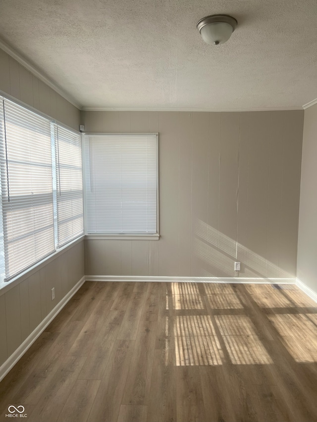 empty room with crown molding, hardwood / wood-style floors, and a textured ceiling