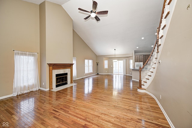 unfurnished living room featuring high vaulted ceiling, light hardwood / wood-style floors, and ceiling fan