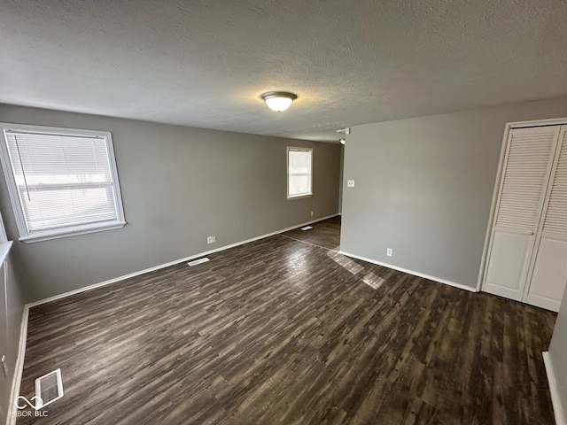 unfurnished room with dark hardwood / wood-style flooring and a textured ceiling