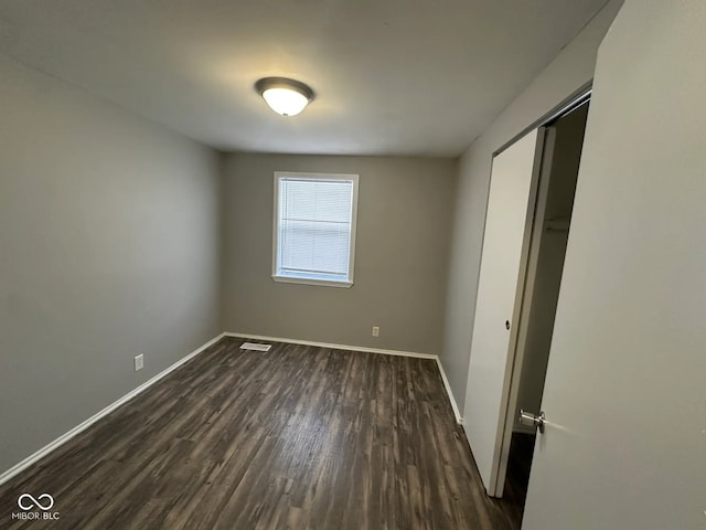 unfurnished bedroom featuring dark hardwood / wood-style flooring and a closet