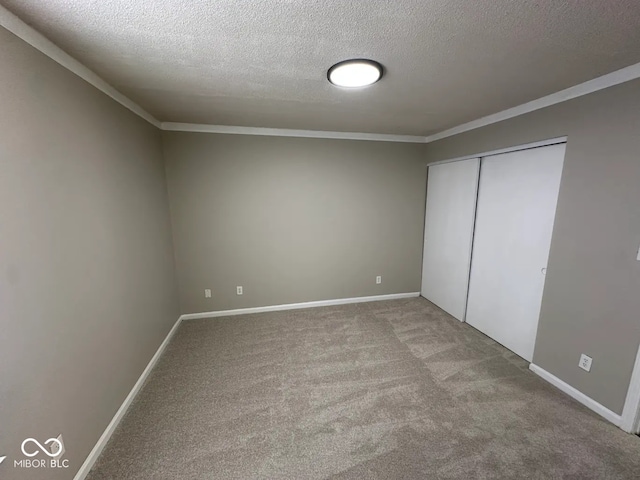 unfurnished bedroom featuring ornamental molding, a closet, a textured ceiling, and carpet