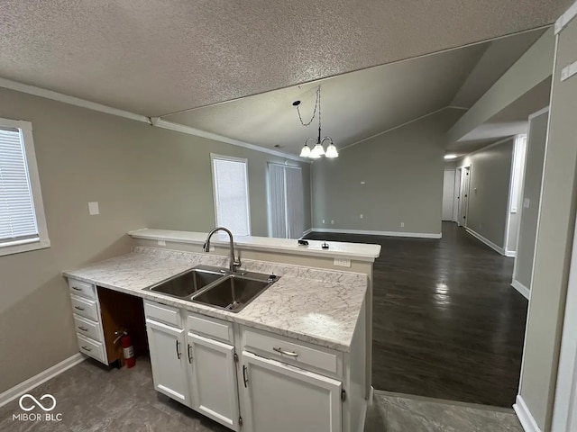 kitchen with sink, white cabinetry, light stone counters, hanging light fixtures, and a textured ceiling