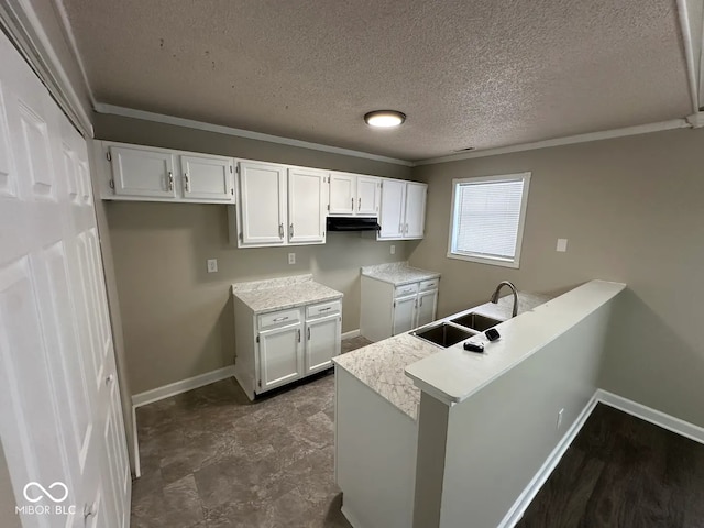 kitchen with sink, a textured ceiling, kitchen peninsula, and white cabinets