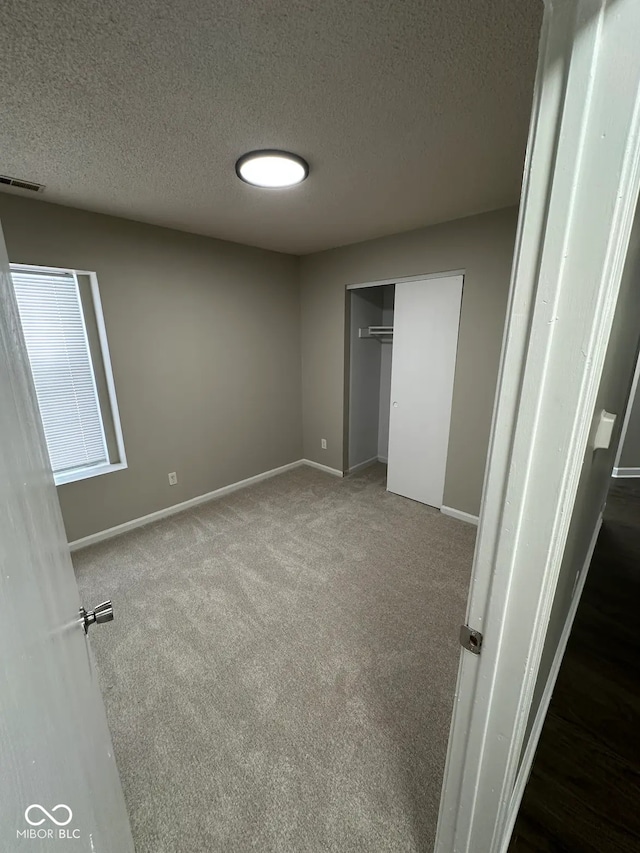 unfurnished bedroom featuring a closet, a textured ceiling, and dark colored carpet