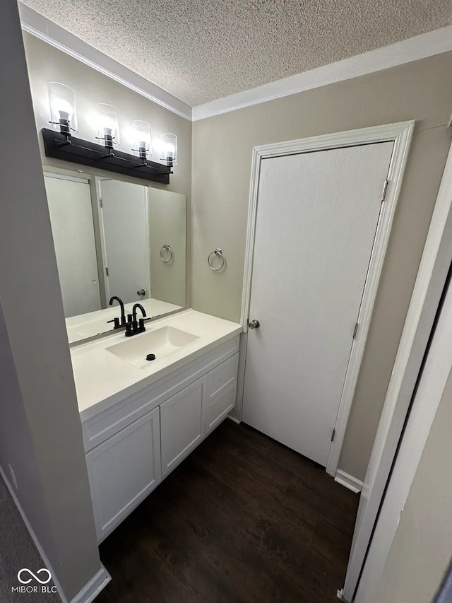 bathroom with vanity, wood-type flooring, ornamental molding, and a textured ceiling