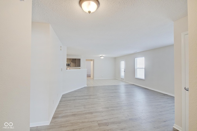 unfurnished room with light hardwood / wood-style flooring and a textured ceiling