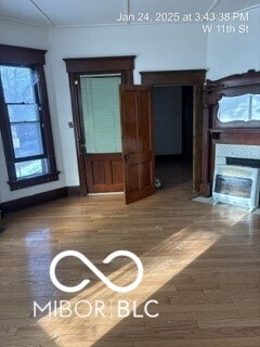 unfurnished living room featuring hardwood / wood-style floors and crown molding