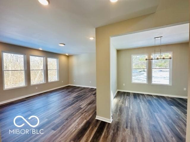 spare room with dark hardwood / wood-style flooring and a notable chandelier