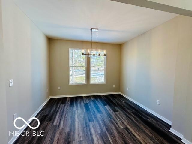 unfurnished dining area featuring dark wood-type flooring and a chandelier