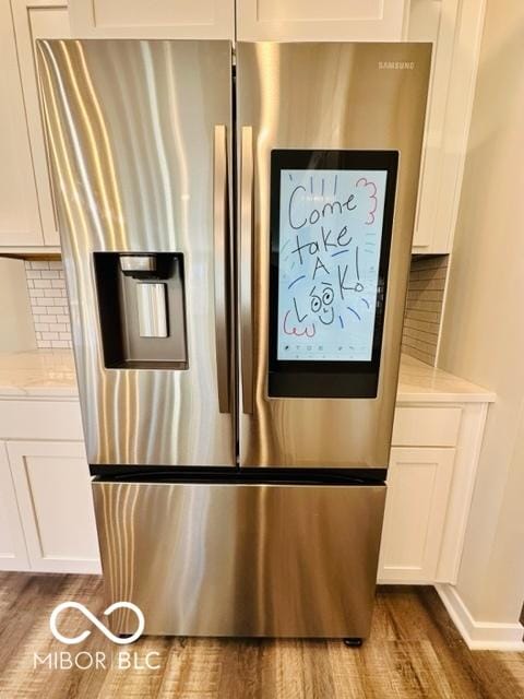 room details featuring stainless steel refrigerator with ice dispenser, white cabinetry, light stone counters, dark hardwood / wood-style floors, and decorative backsplash