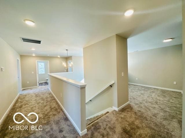 hallway with a chandelier and carpet floors