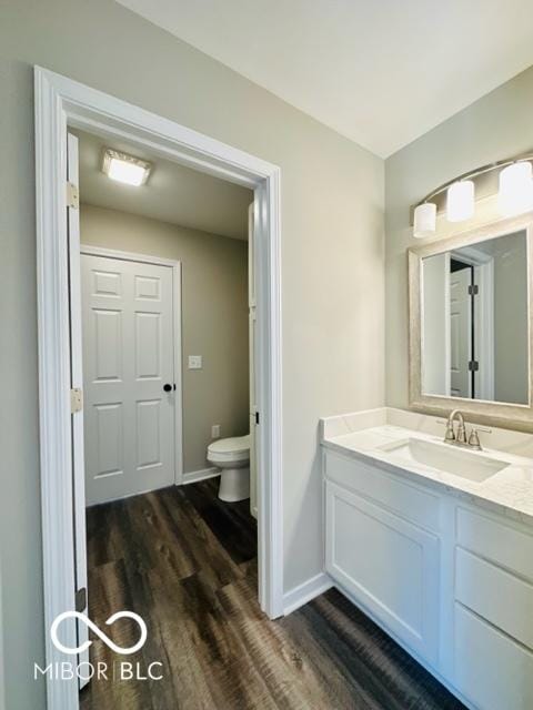 bathroom with wood-type flooring, vanity, and toilet