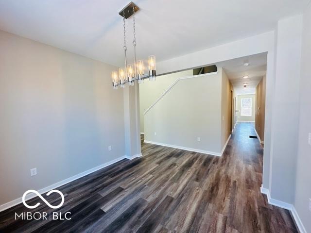 unfurnished dining area featuring dark wood-type flooring and a notable chandelier