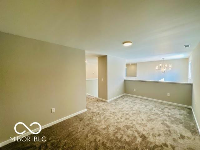 carpeted spare room with a notable chandelier