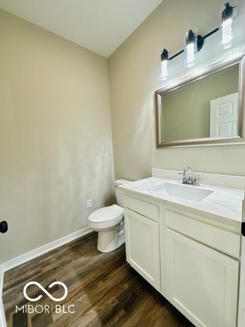 bathroom featuring vanity, wood-type flooring, and toilet