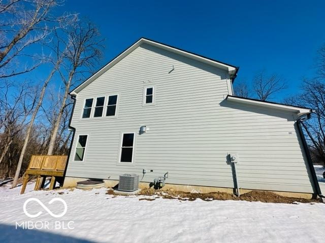 snow covered back of property with central AC