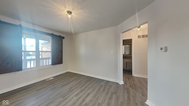 empty room featuring wood-type flooring and a textured ceiling