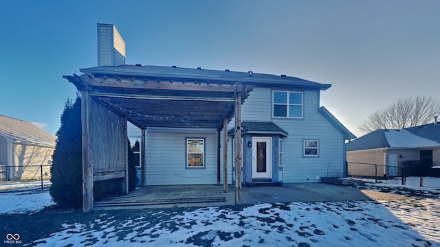 snow covered rear of property with a patio