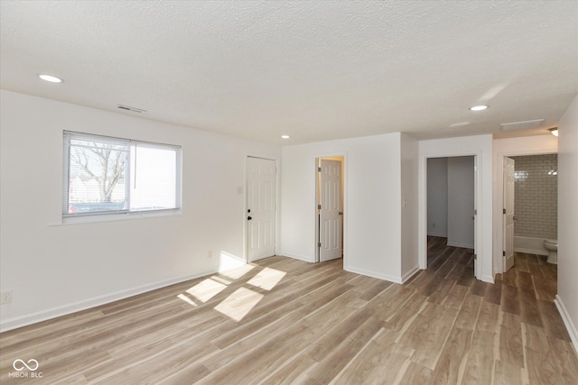 unfurnished room featuring a textured ceiling and light hardwood / wood-style flooring