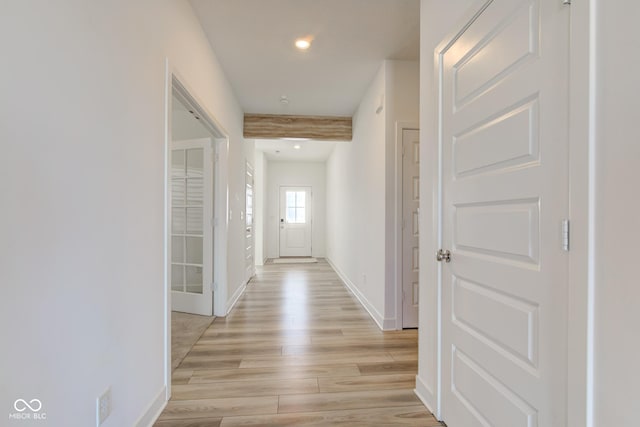 hallway featuring beam ceiling and light hardwood / wood-style flooring