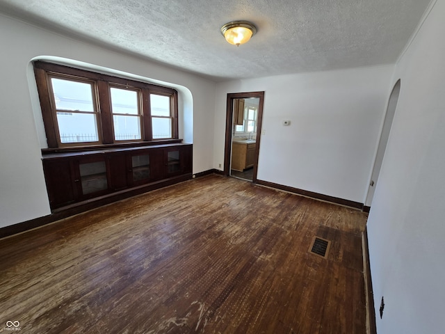 empty room with dark wood-type flooring and a textured ceiling