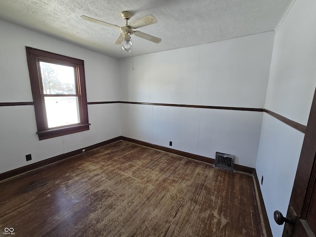 unfurnished room featuring ceiling fan, dark wood-type flooring, and a textured ceiling