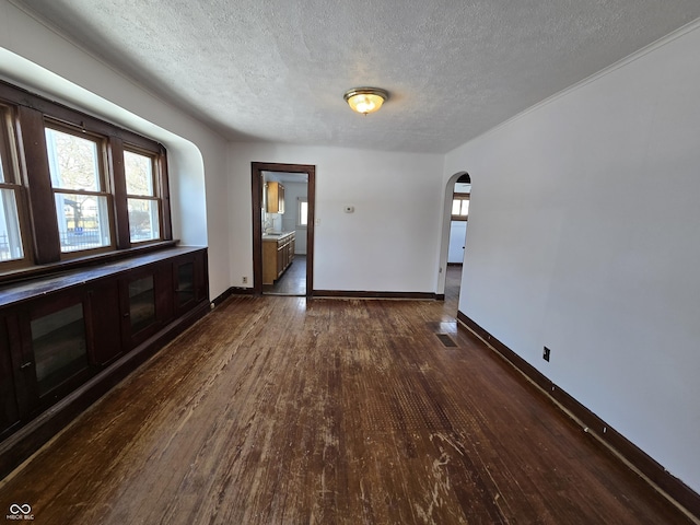 spare room featuring plenty of natural light, a textured ceiling, and dark hardwood / wood-style flooring