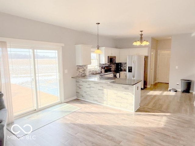 kitchen featuring decorative light fixtures, stainless steel appliances, decorative backsplash, and white cabinets