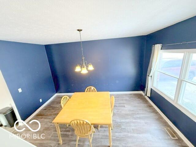 dining area with hardwood / wood-style flooring and a notable chandelier