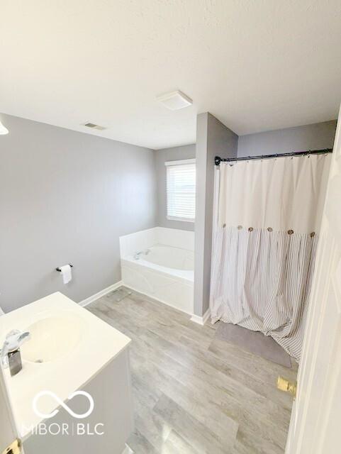 bathroom featuring hardwood / wood-style floors, shower with separate bathtub, and sink