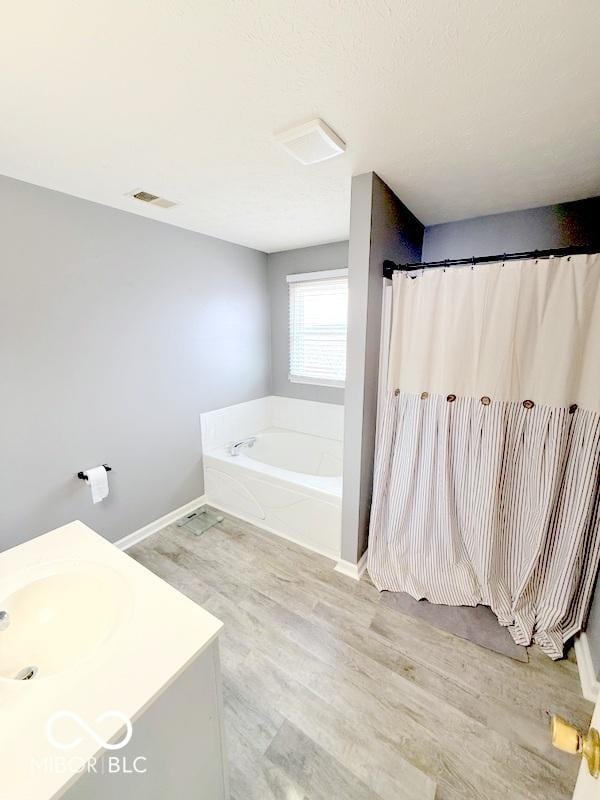 bathroom featuring wood-type flooring, shower with separate bathtub, and vanity