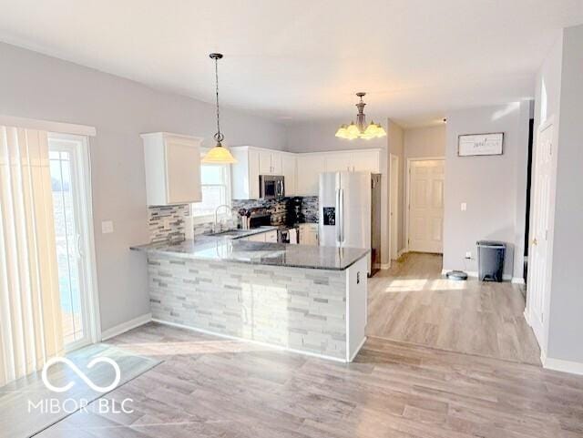 kitchen with pendant lighting, stainless steel appliances, white cabinets, decorative backsplash, and kitchen peninsula