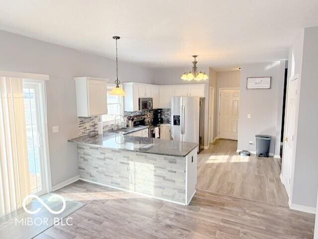 kitchen featuring sink, appliances with stainless steel finishes, hanging light fixtures, white cabinets, and kitchen peninsula