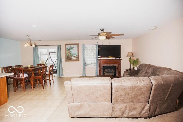 living room with ceiling fan with notable chandelier and a fireplace