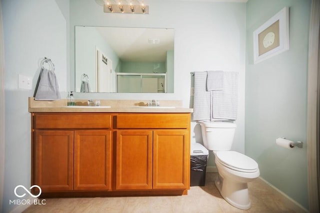 bathroom with tile patterned flooring, vanity, a shower with door, and toilet