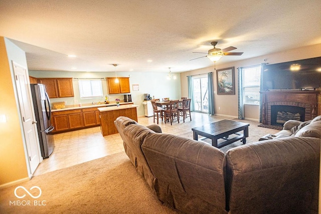 living room with ceiling fan, plenty of natural light, a fireplace, and a textured ceiling