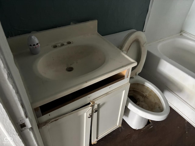 bathroom with vanity, a tub to relax in, wood-type flooring, and toilet