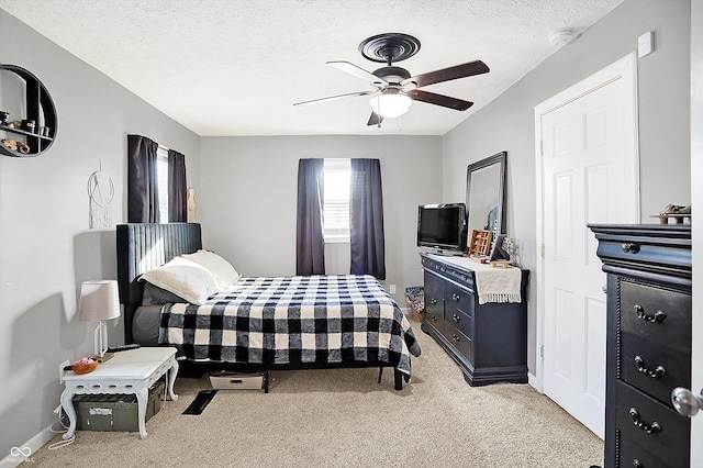 carpeted bedroom with ceiling fan and a textured ceiling