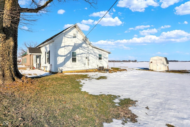 back of house with central AC, a storage unit, and a yard