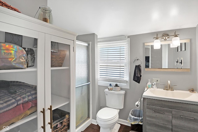 bathroom with vanity, hardwood / wood-style flooring, a shower with door, and toilet