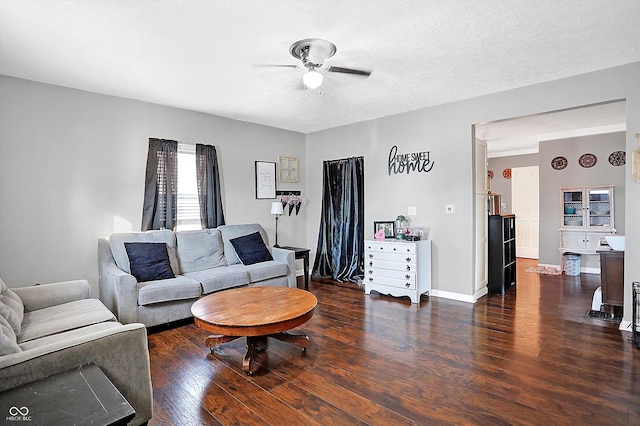 living room with dark hardwood / wood-style flooring, ceiling fan, and a textured ceiling