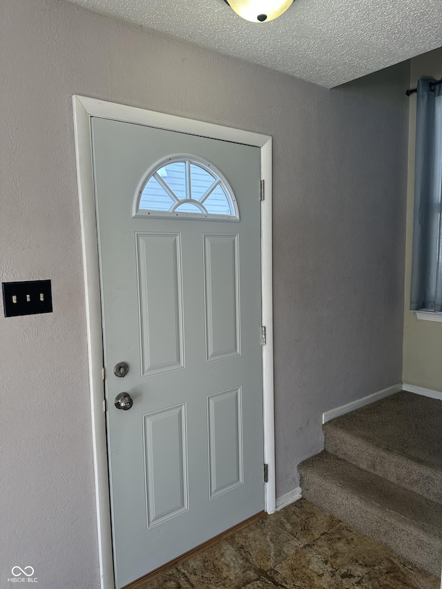 foyer entrance with a textured ceiling